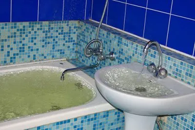 Overflowing bathtub and sink in a tiled bathroom